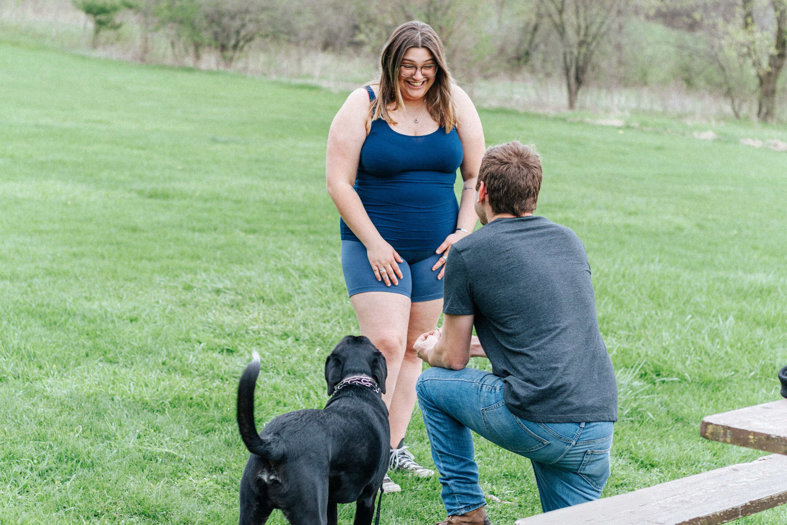 Max kneels on one knee, proposing to Caitlyn during their surprise engagement photos, capturing a heartfelt moment.