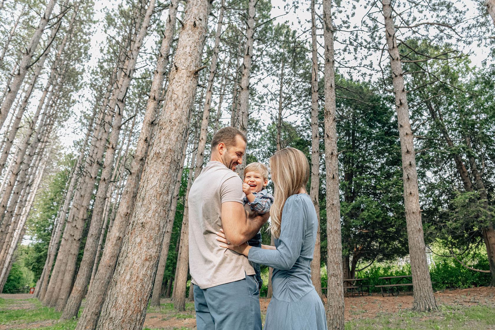 Family walking through pine trees during Retzer Nature Center family session in Waukesha, WI.